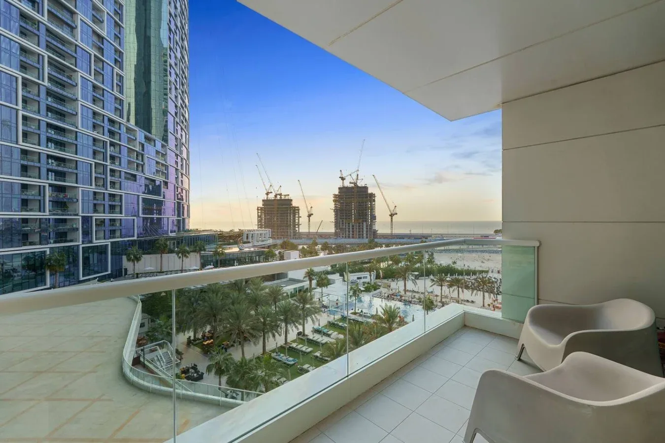 Un balcón ofrece vistas a jardines y edificios en construcción bajo un cielo despejado.