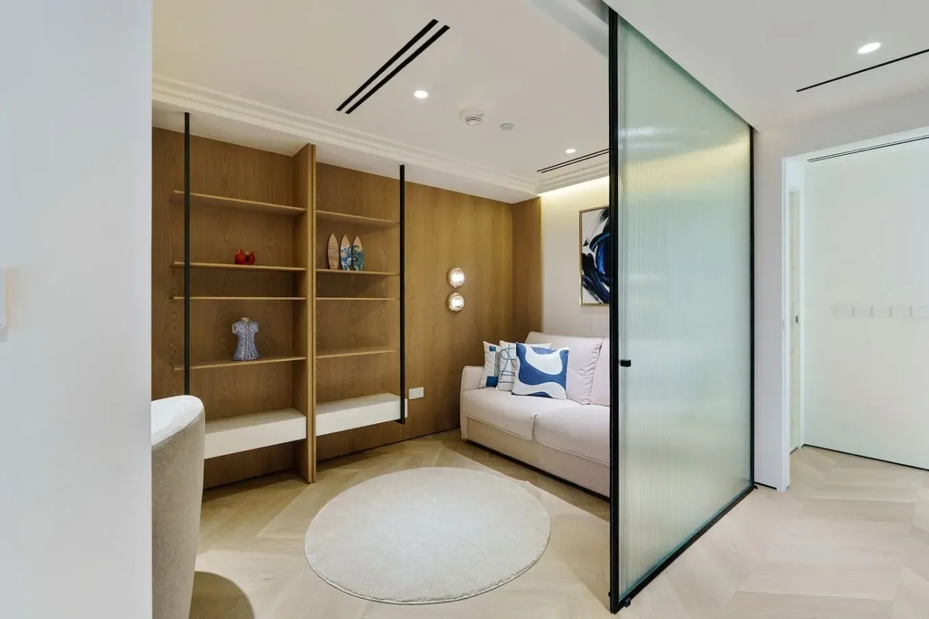 Una zona de estar moderna con estanterías de madera empotradas y asientos claros.