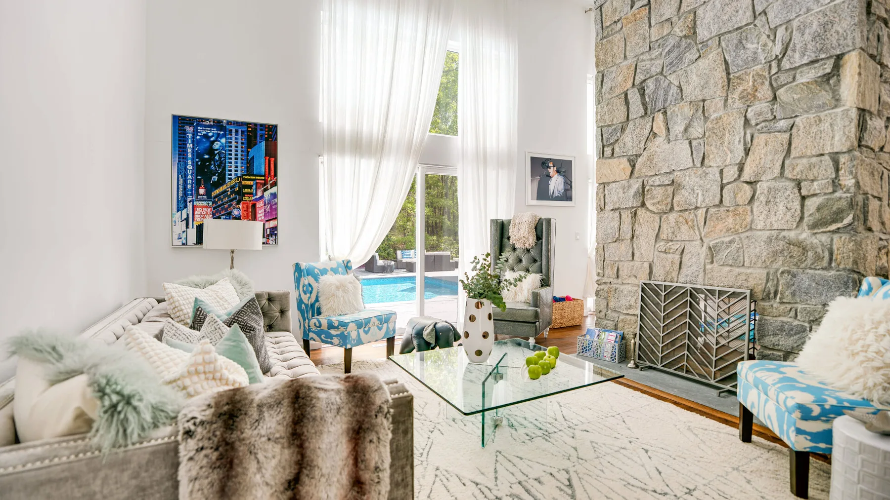 Una sala luminosa con asientos, una mesa de centro de vidrio y una pared de piedra.