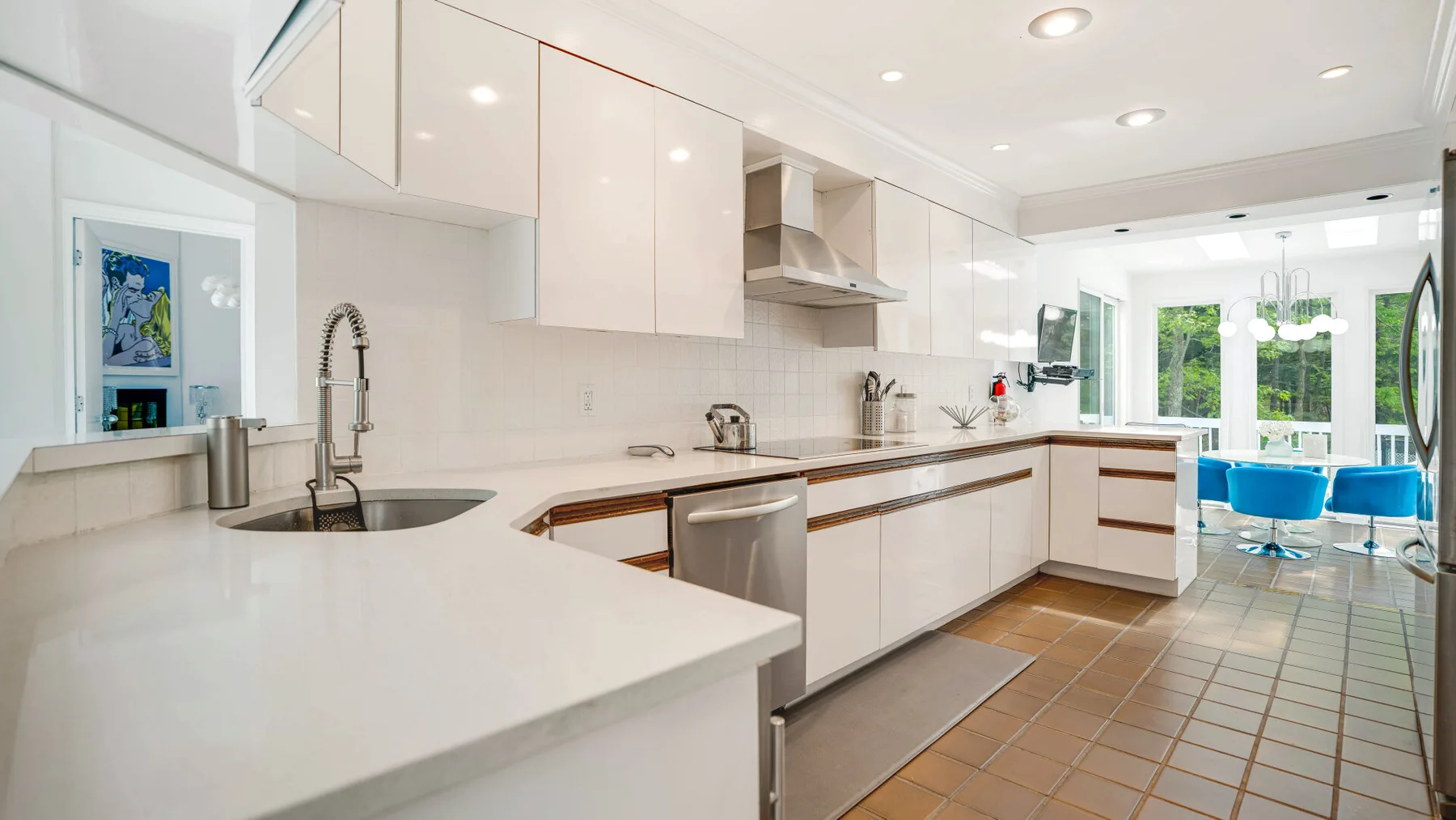 A bright kitchen with white cabinets, a long counter, and a sink.