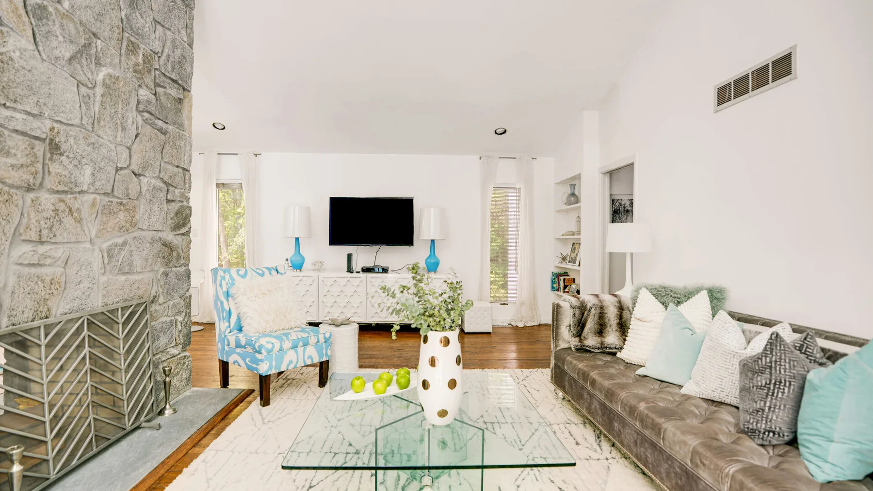 A bright living room with seating around a glass coffee table and television.