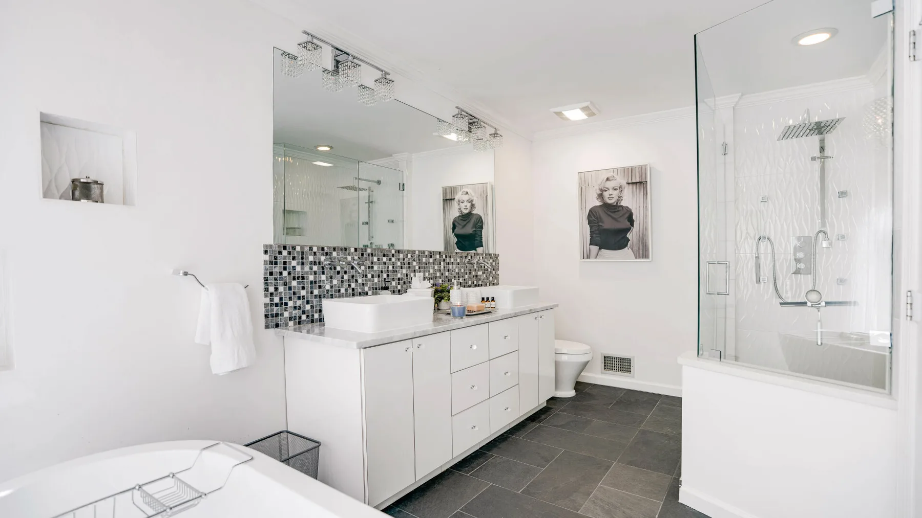 A bright bathroom with a long vanity and a glass-enclosed shower.
