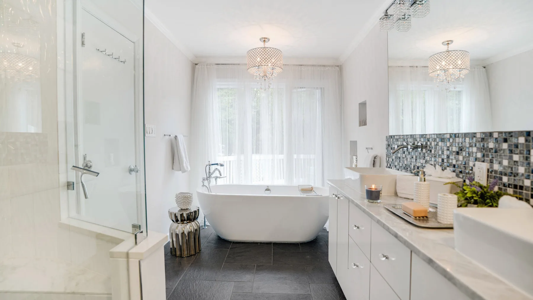 A bright bathroom with a freestanding bathtub, glass shower, and long vanity.
