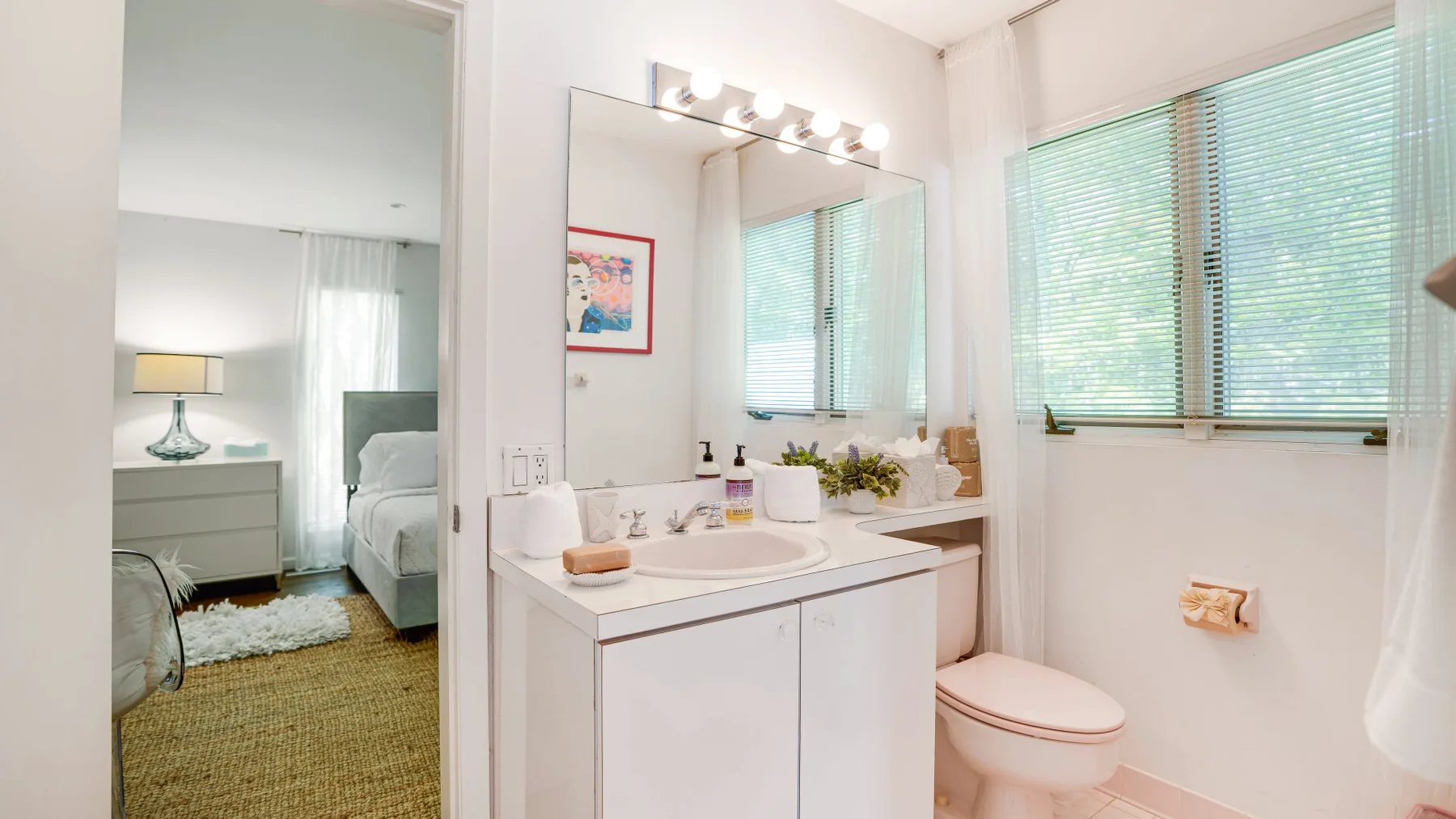 A bright bathroom with a long vanity and large windows.
