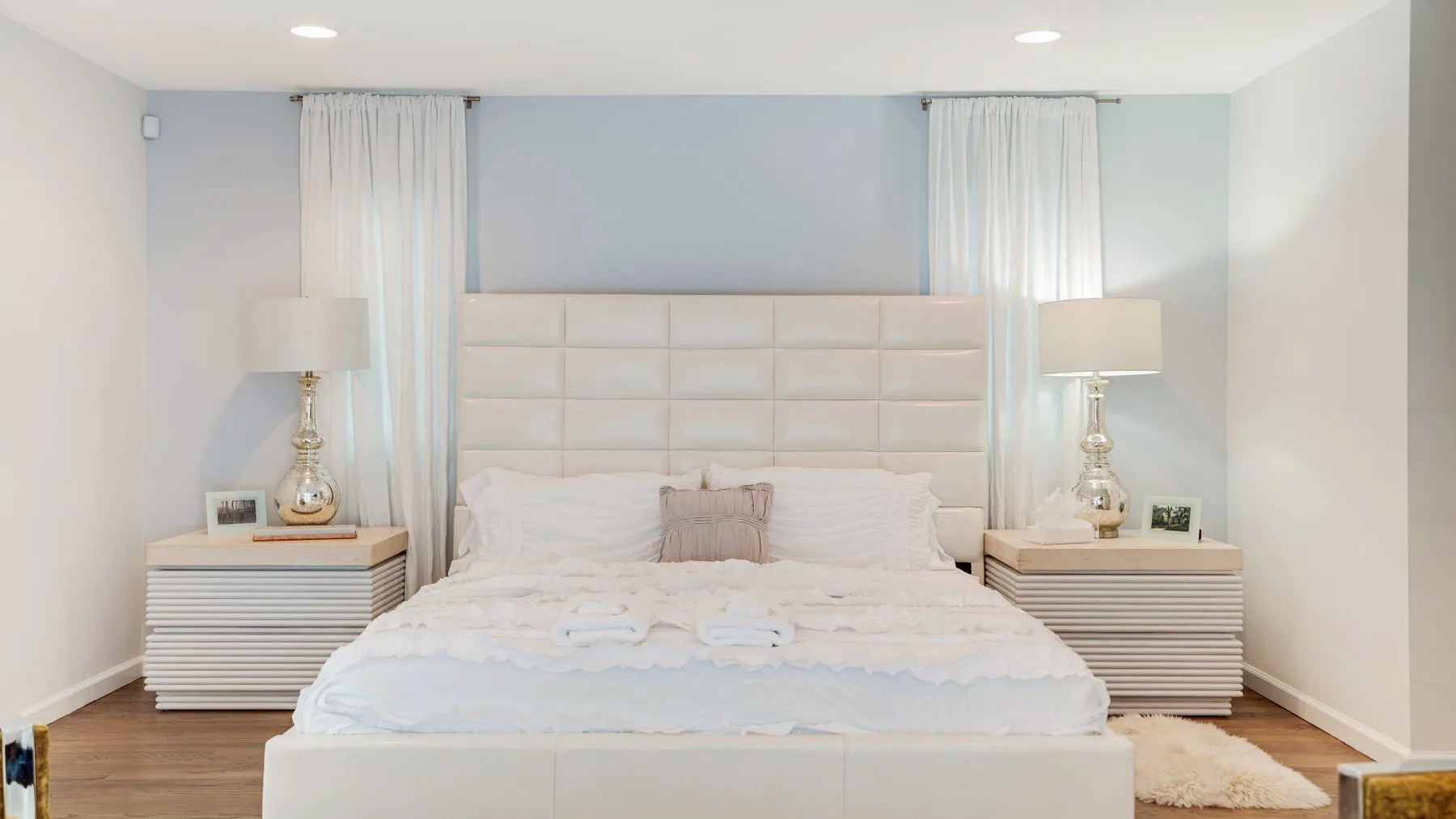 A bright bedroom with a neatly made bed between two bedside tables.