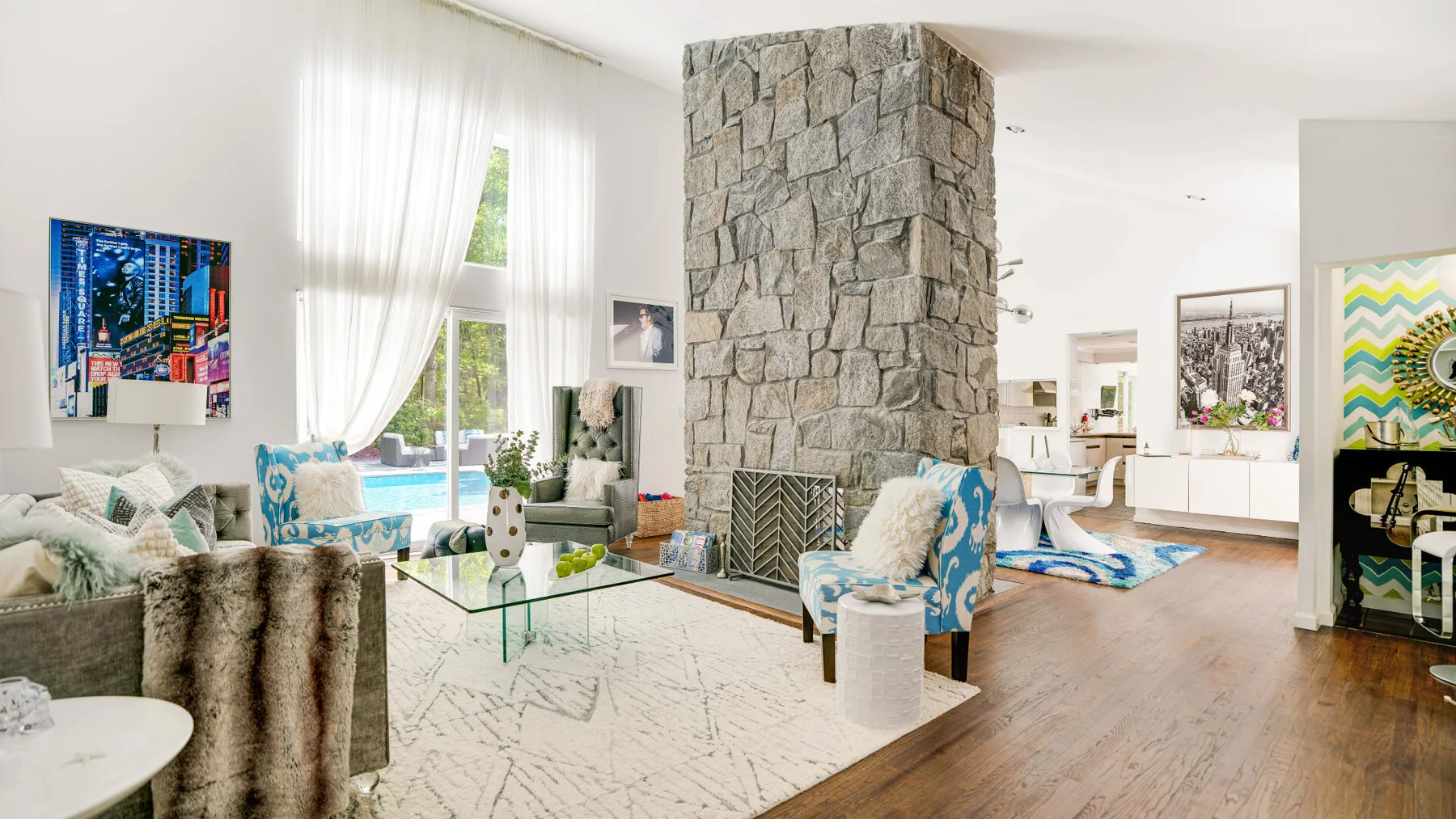 A bright living room with seating around a glass coffee table and a stone fireplace.