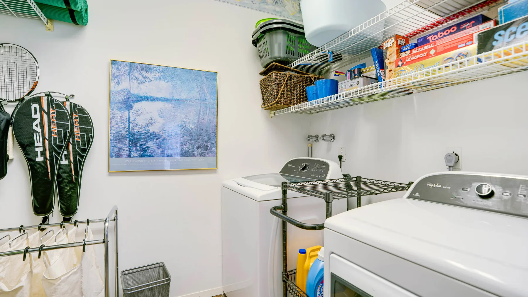 A laundry room with washing machines, a drying rack, and storage shelves.