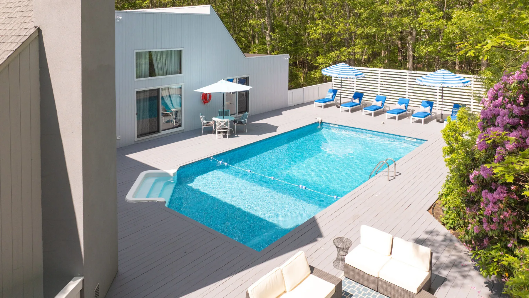 An outdoor pool and surrounding deck with seating and umbrellas.