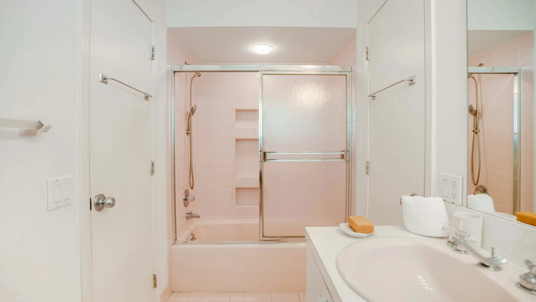A bright bathroom with a bathtub, shower, and sink.