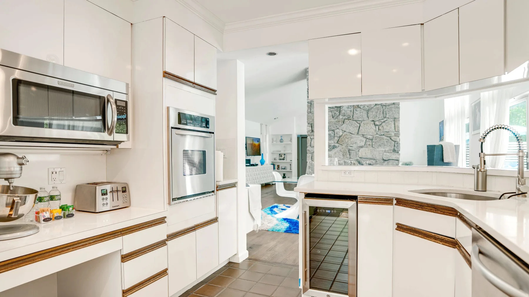 A bright kitchen with white cabinetry, built-in appliances, and a central counter.