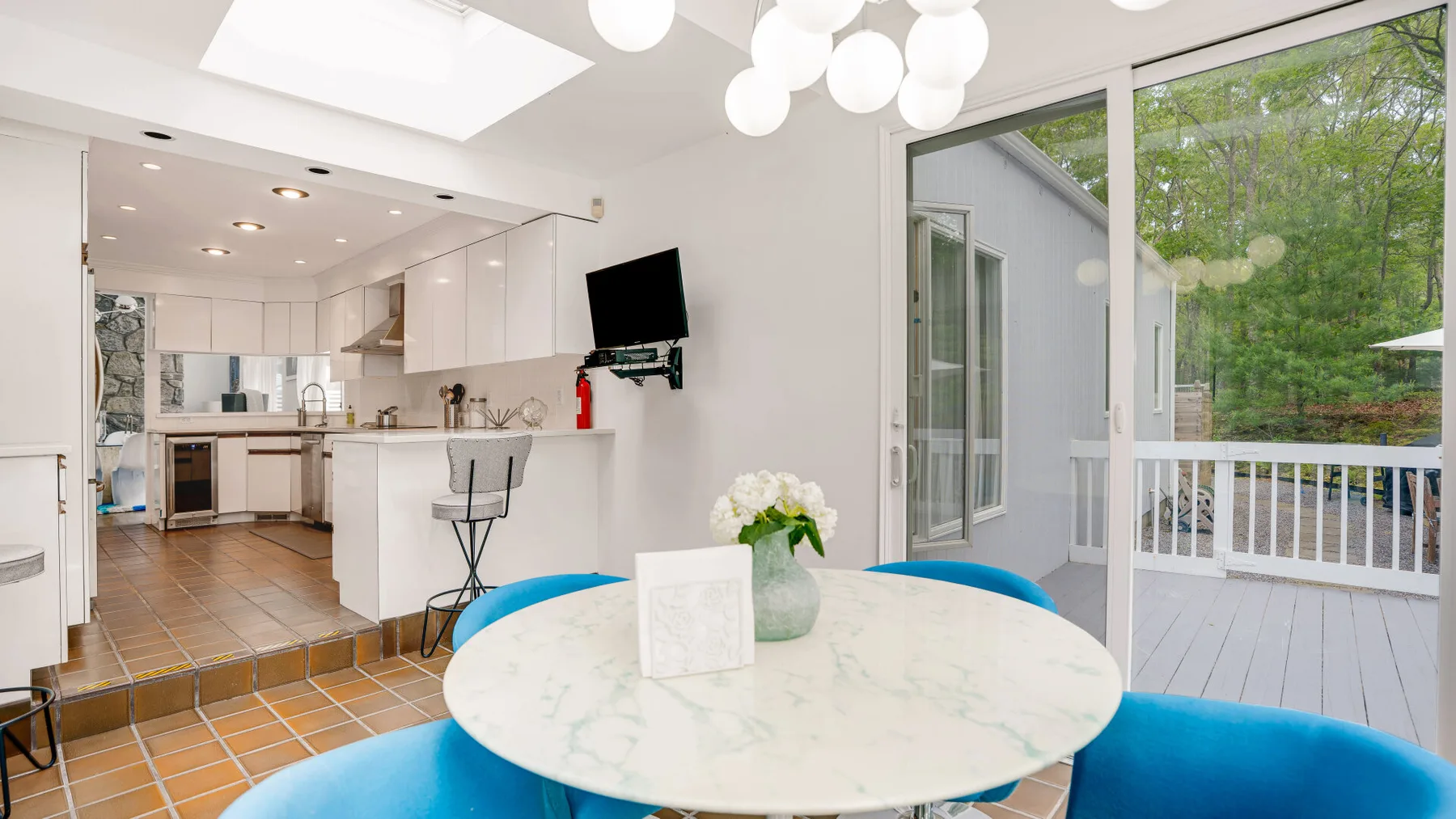 A bright dining area with a round table beside sliding glass doors opening onto a deck.