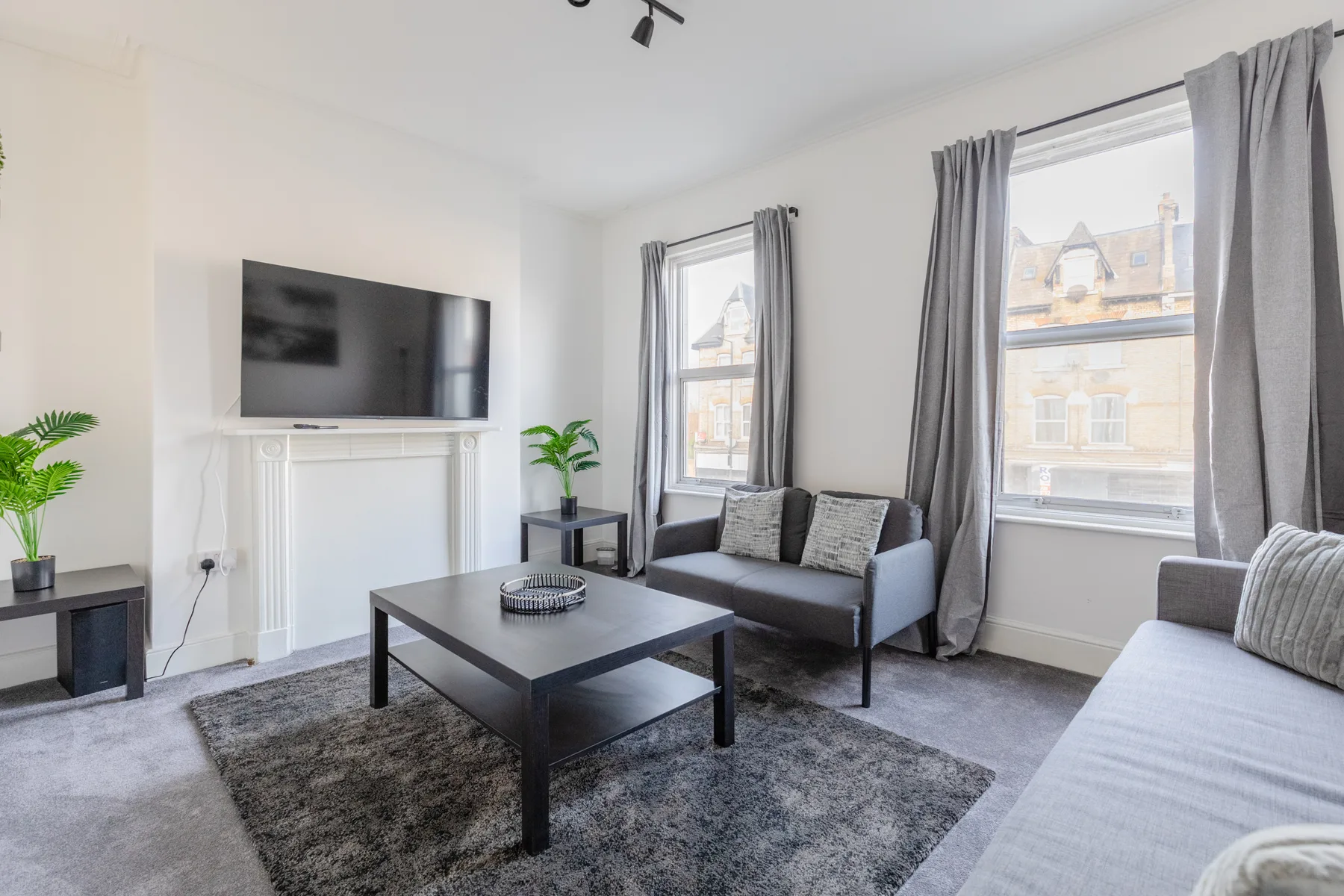 A bright living room with seating, a coffee table, and large windows.
