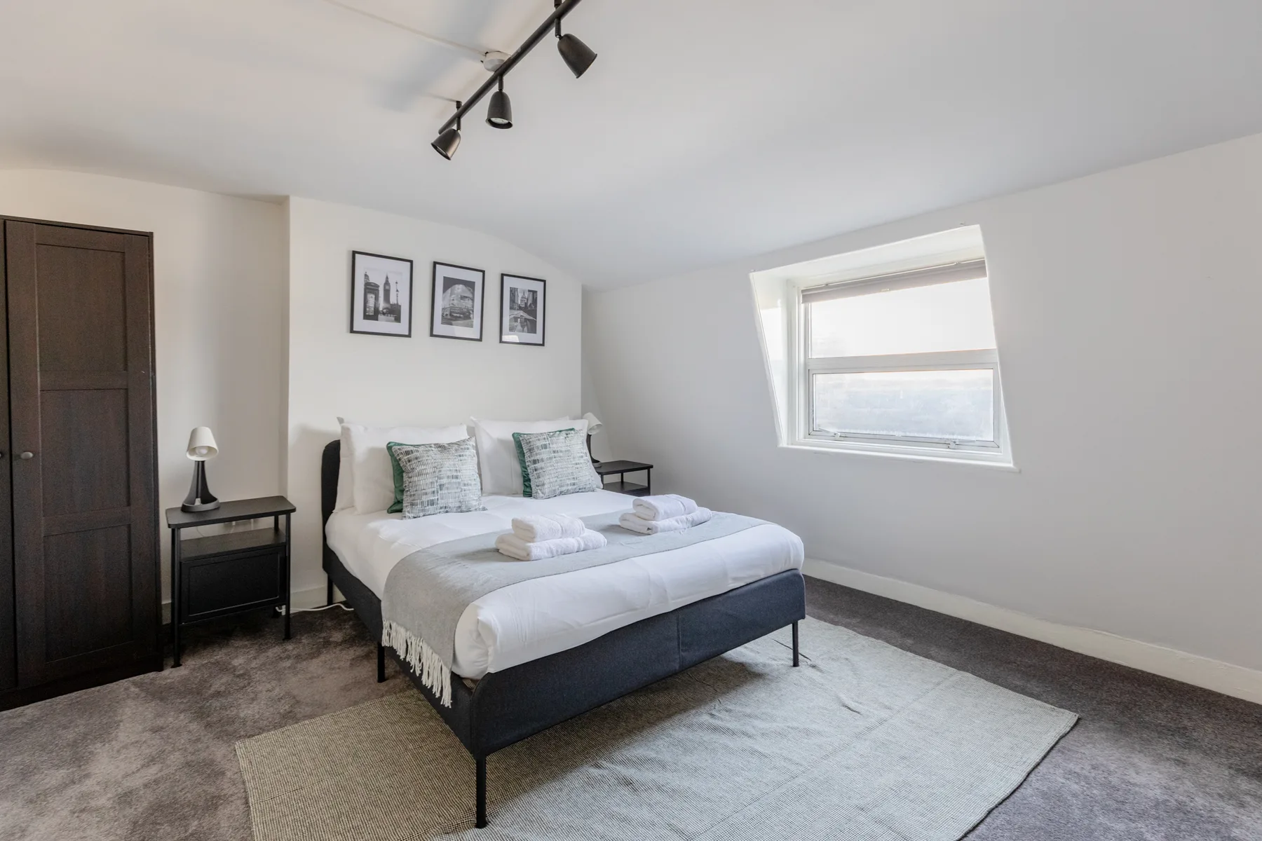 A bedroom with a neatly made bed and a window.