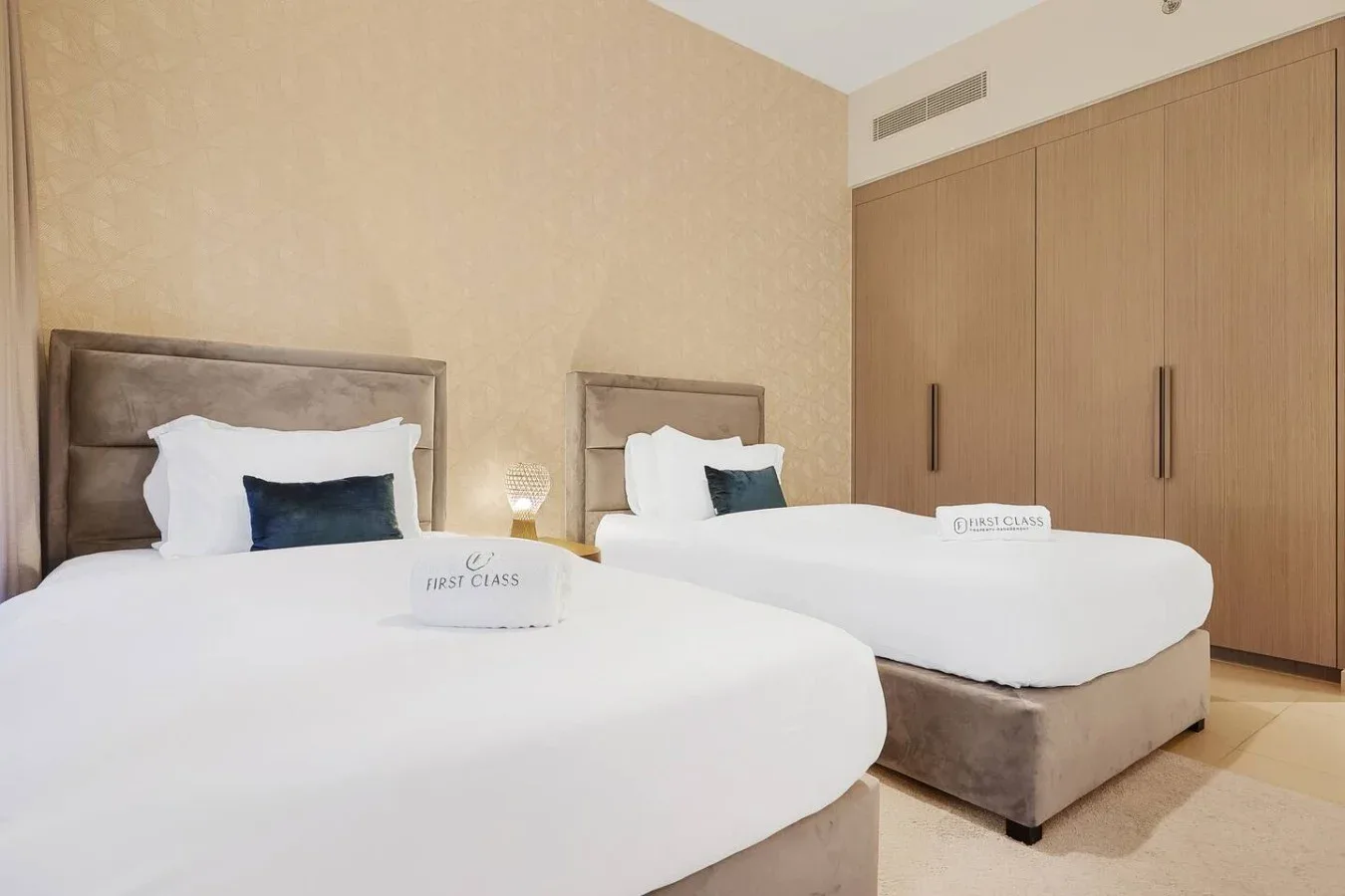 Un dormitorio con dos camas vestidas de blanco y armarios de madera empotrados.