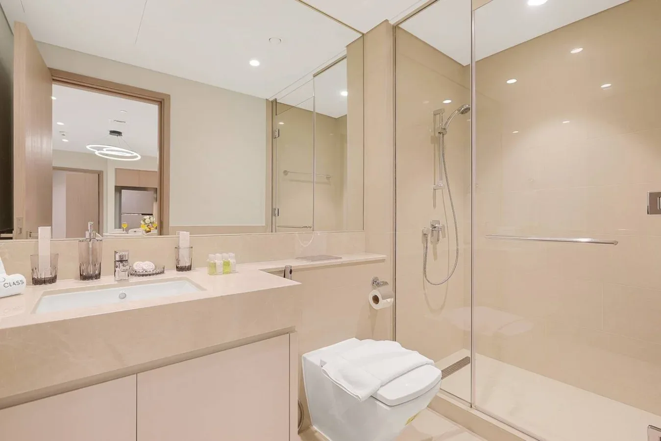 Un baño luminoso con tocador, espejo grande y ducha de vidrio.
