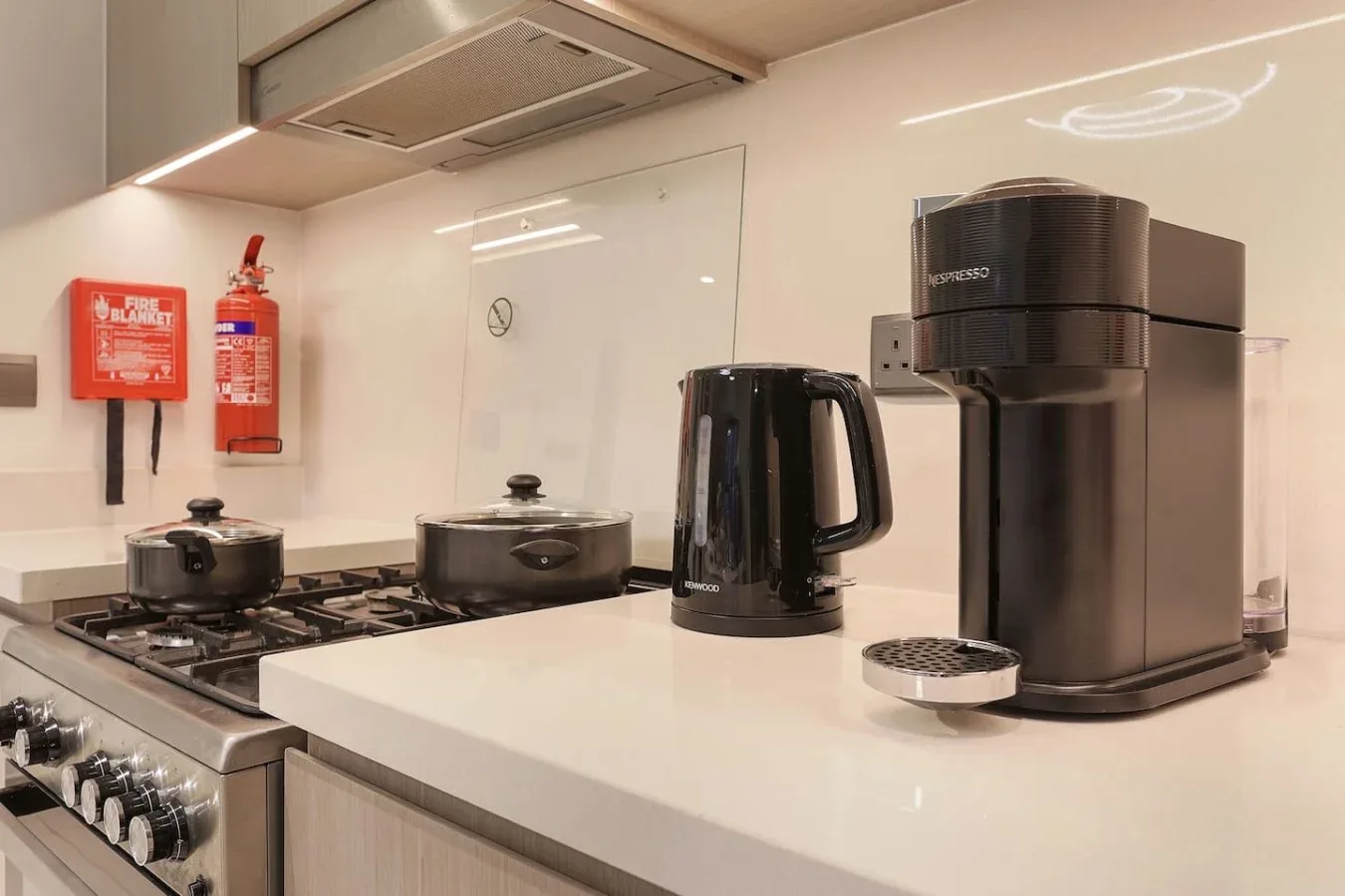 Una encimera de cocina moderna con cafetera y hervidor junto a la estufa.