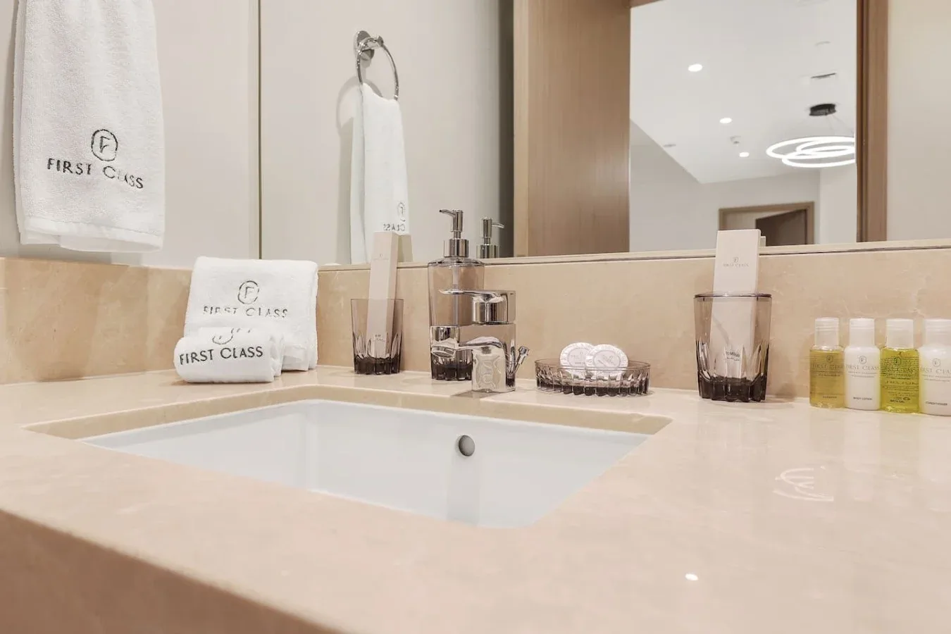 Un tocador de baño con lavabo, espejo, toallas y artículos de aseo sobre la encimera.