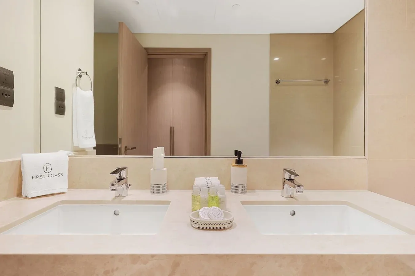 Un lavabo de baño con dos lavabos, artículos de aseo y un gran espejo.