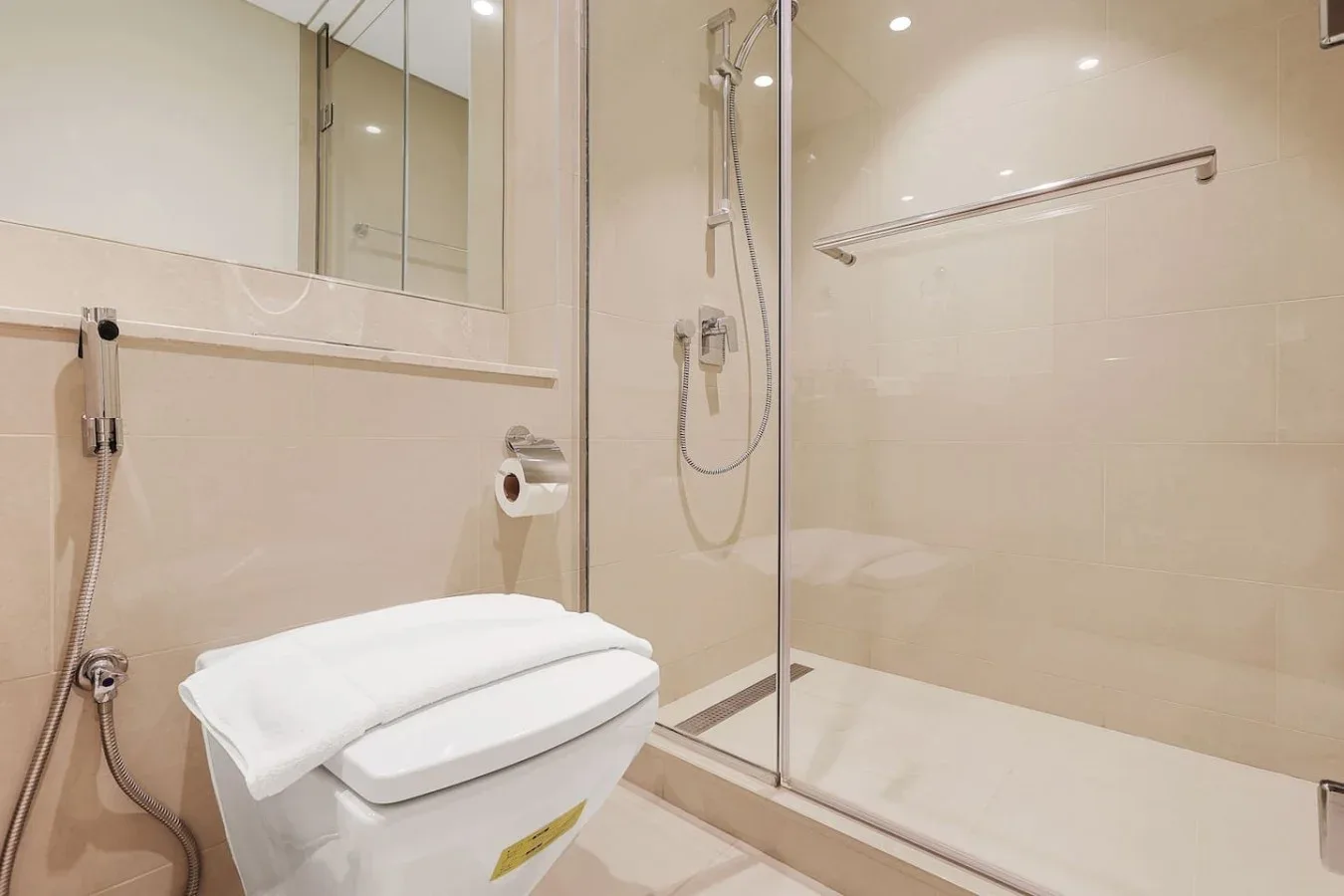 Un baño alicatado con un inodoro junto a una ducha de vidrio.