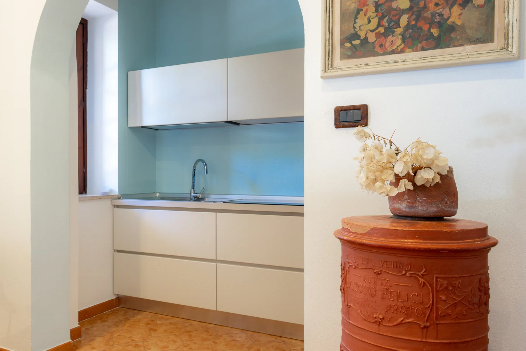 Una cocina compacta con gabinetes claros, un fregadero y un salpicadero azul.