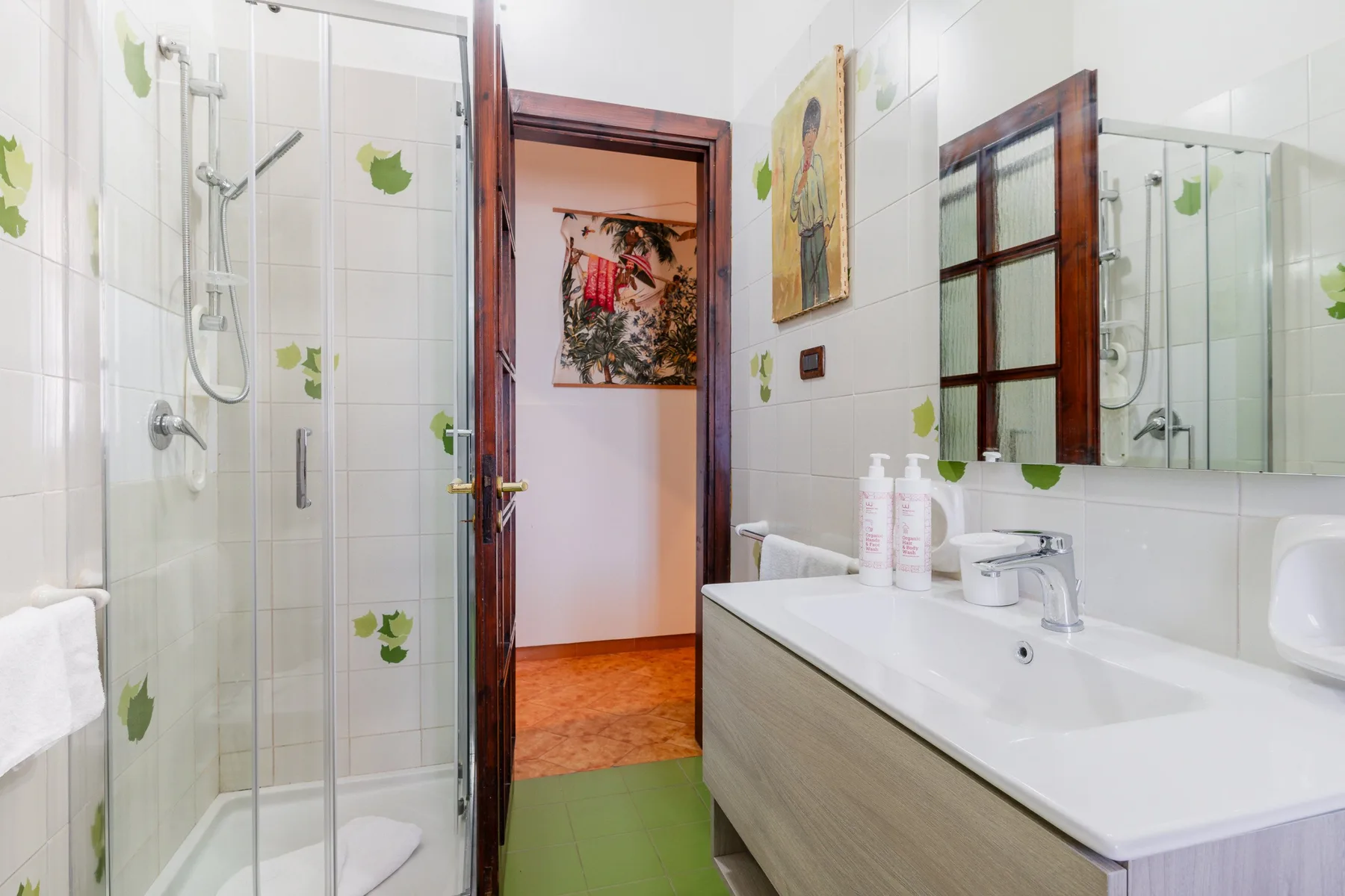 Un baño alicatado con ducha de vidrio y una encimera larga con lavabo.