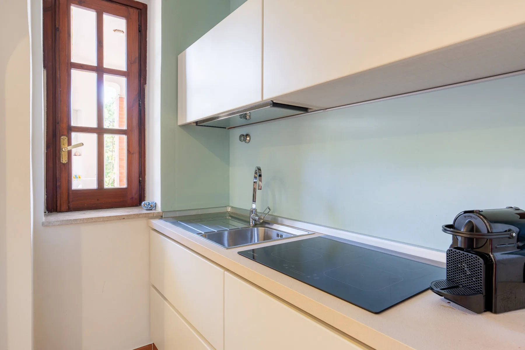 Una cocina moderna con fregadero, encimera y una ventana con marco de madera.