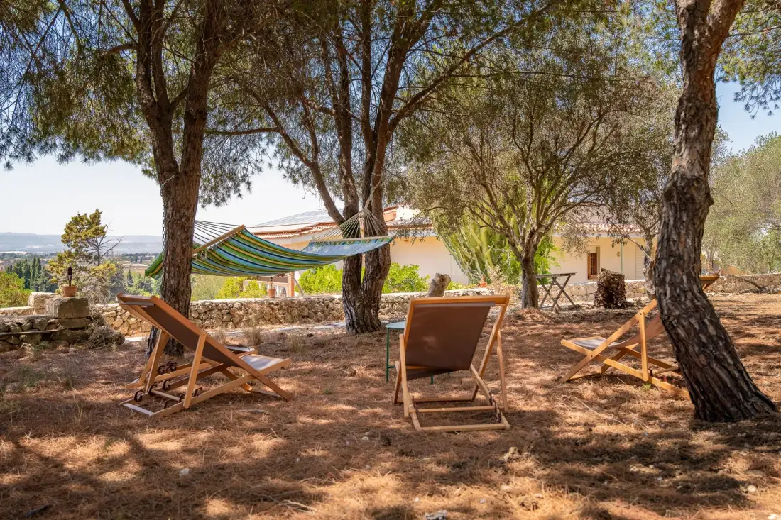 Una zona de estar al aire libre bajo los árboles, con una hamaca y vistas al paisaje.