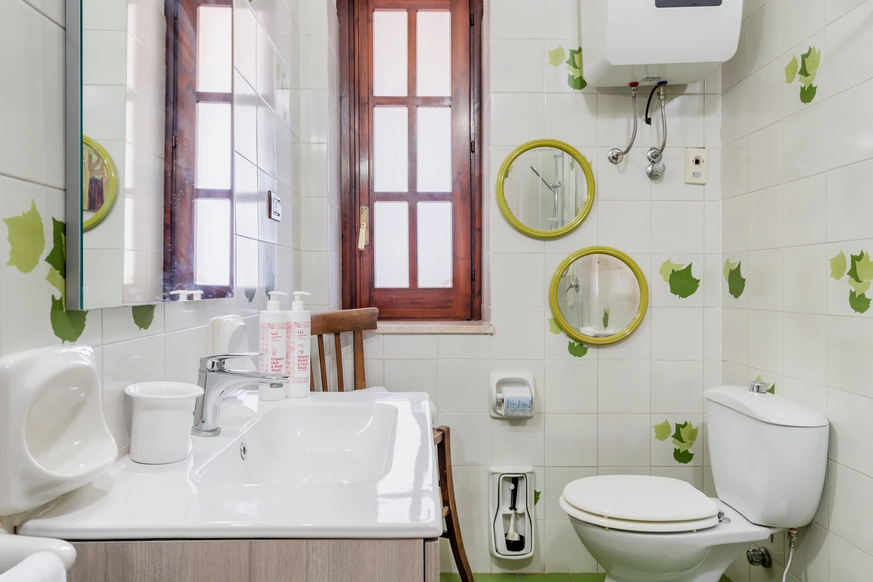 Un baño con azulejos, lavabo, inodoro y espejos redondos en la pared.