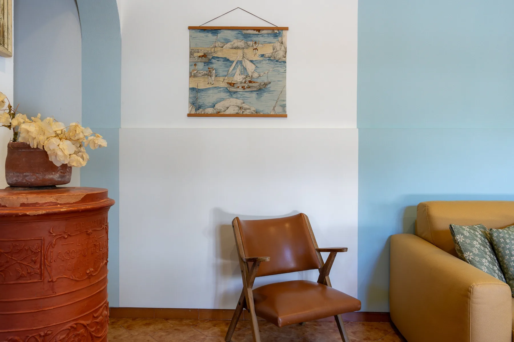 Una sala de estar con asientos, un mueble de madera y un cuadro en la pared.