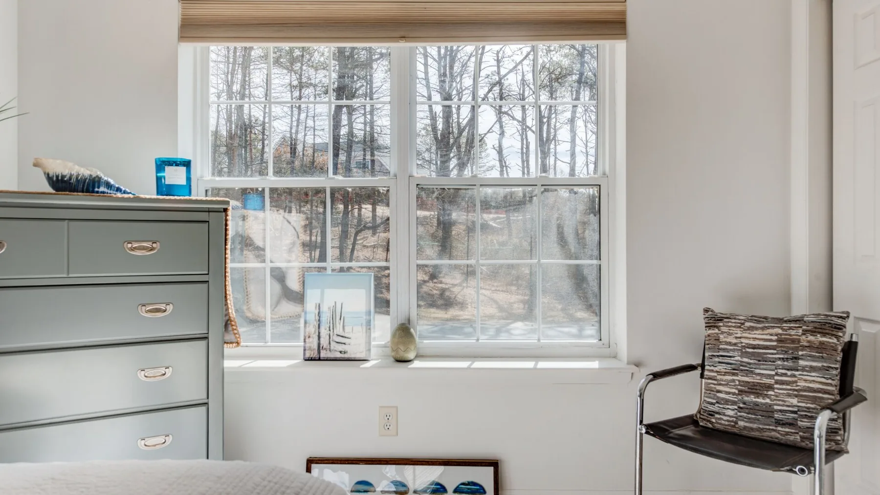 A bright room with a large window overlooking leafless trees.