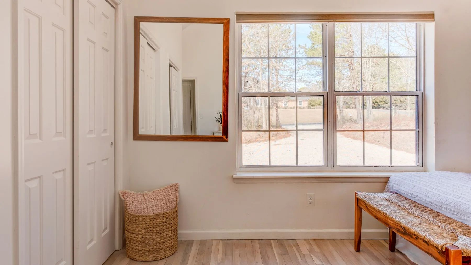 A bright bedroom with a large window and a woven basket.