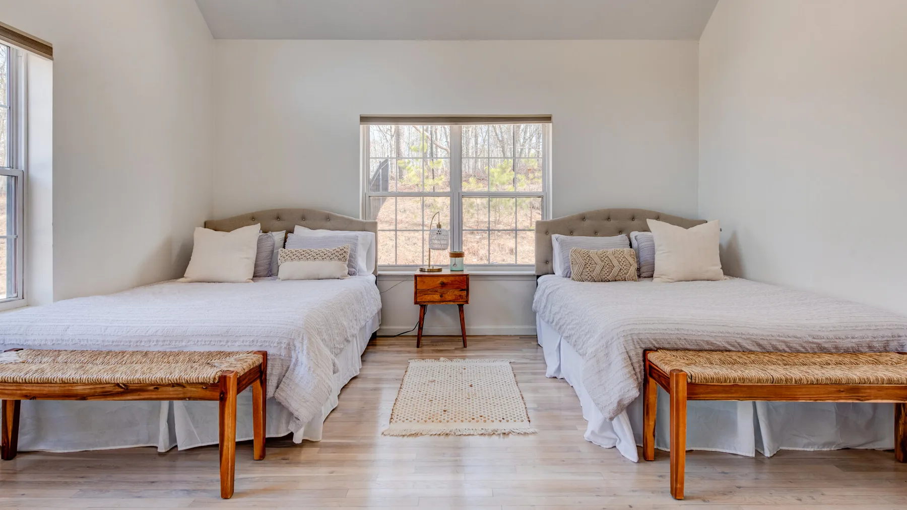 A bright bedroom with two beds and a large window.