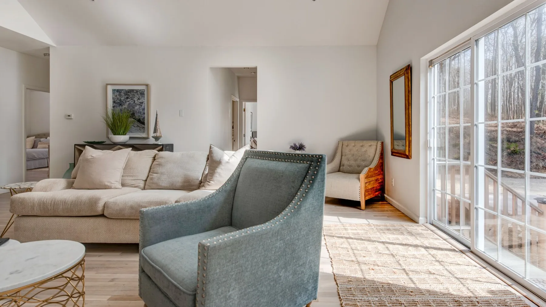 A bright living room with seating beside large windows and a glass door.
