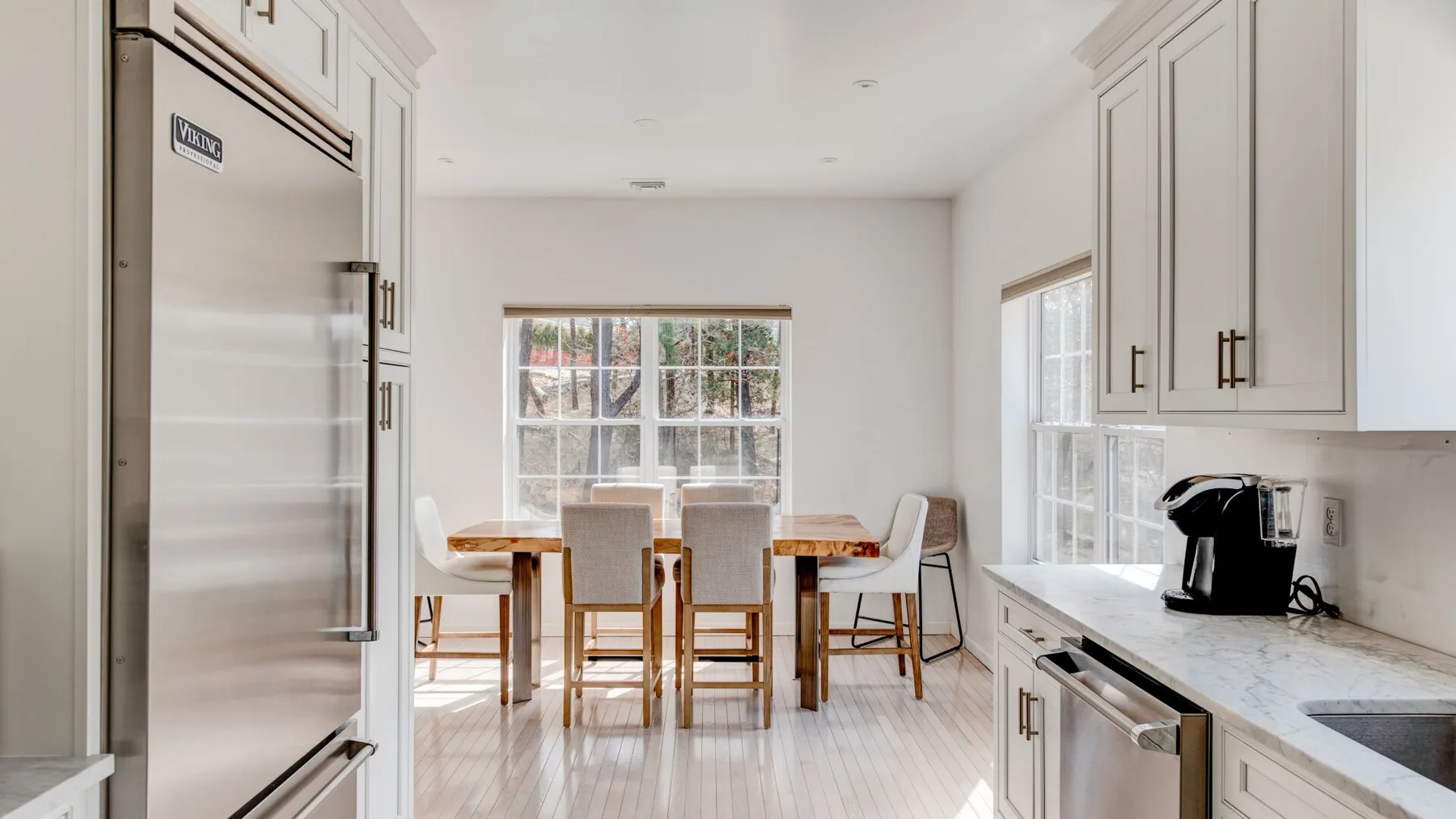 A bright kitchen with a dining table beside a large window.