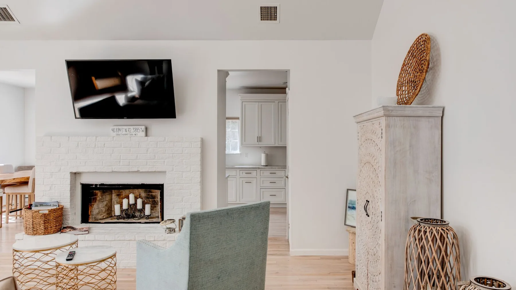 A bright living room with a fireplace, television, and doorway to a kitchen.