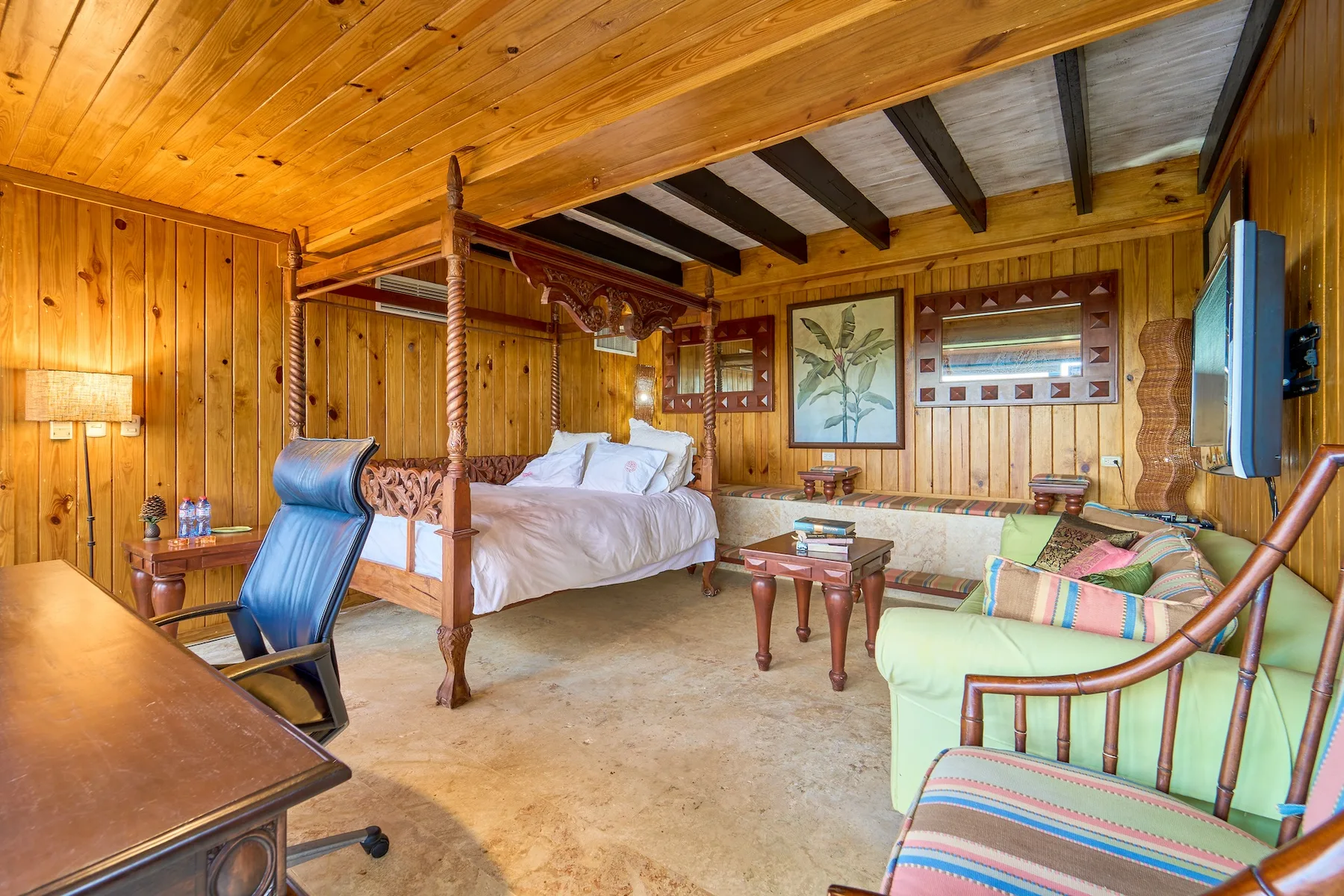 Un dormitorio revestido de madera con cama con dosel y zona de estar.