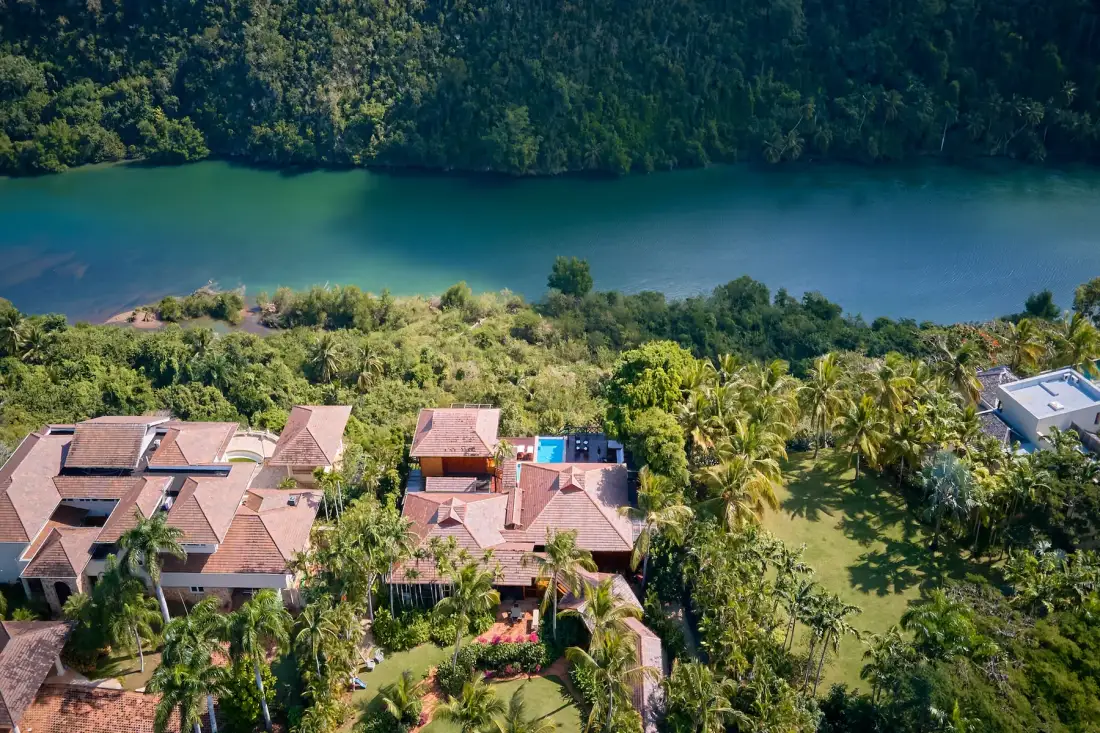Vista aérea de un complejo tropical junto a un lago, rodeado de árboles.