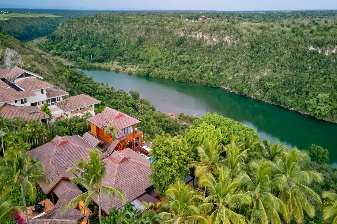 Vista aérea de edificios entre vegetación tropical junto a un río sinuoso.