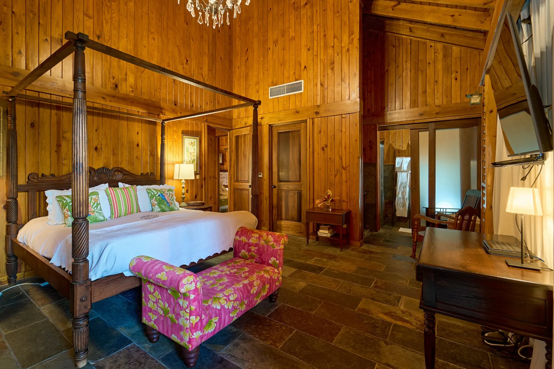 Un dormitorio revestido de madera cuenta con una cama grande y un sillón tapizado de colores.