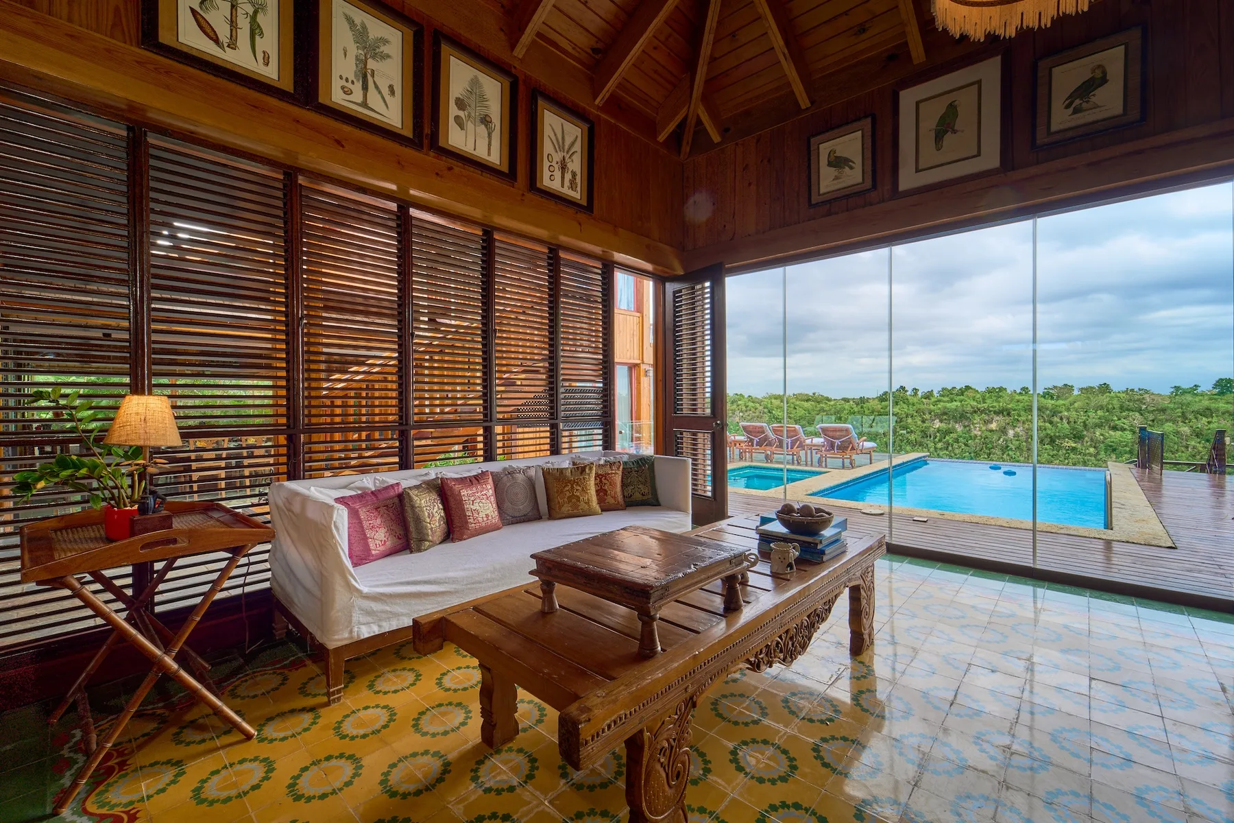 A wood-paneled living room with seating and a view of the pool through glass.