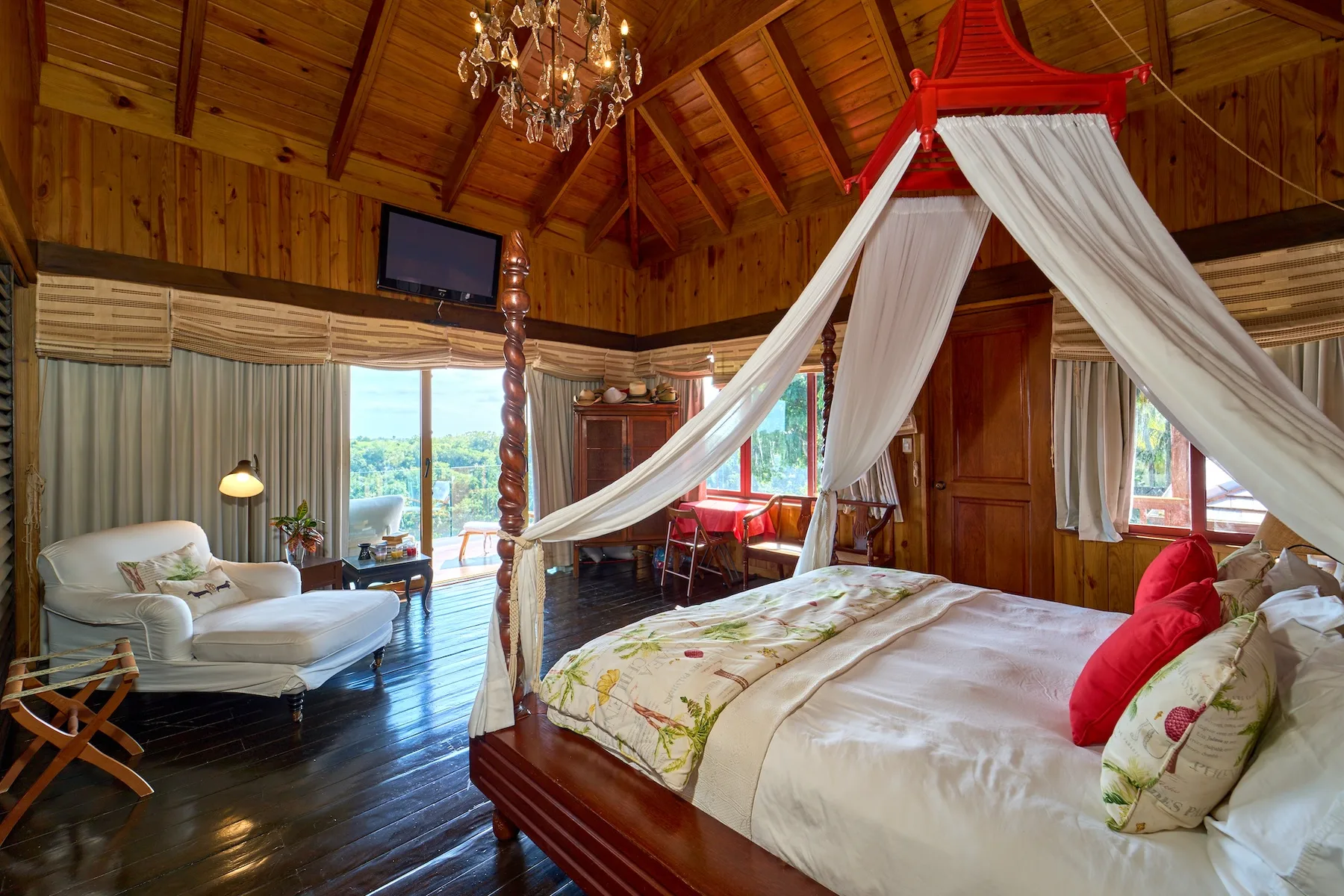 Un dormitorio revestido de madera, con cama con dosel y asientos junto a las ventanas.