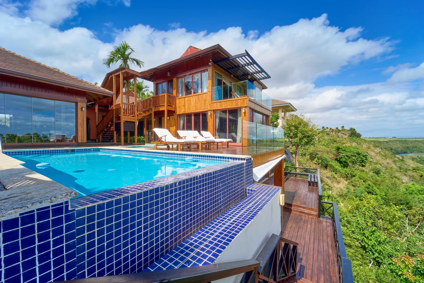 Una casa moderna da a una piscina y a un paisaje costero verde.