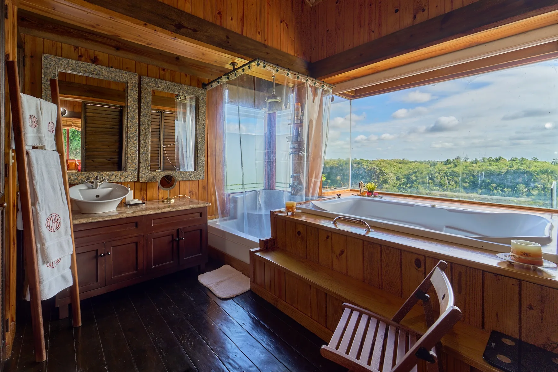 Un baño revestido de madera con una bañera junto a una gran ventana con vistas a la vegetación.