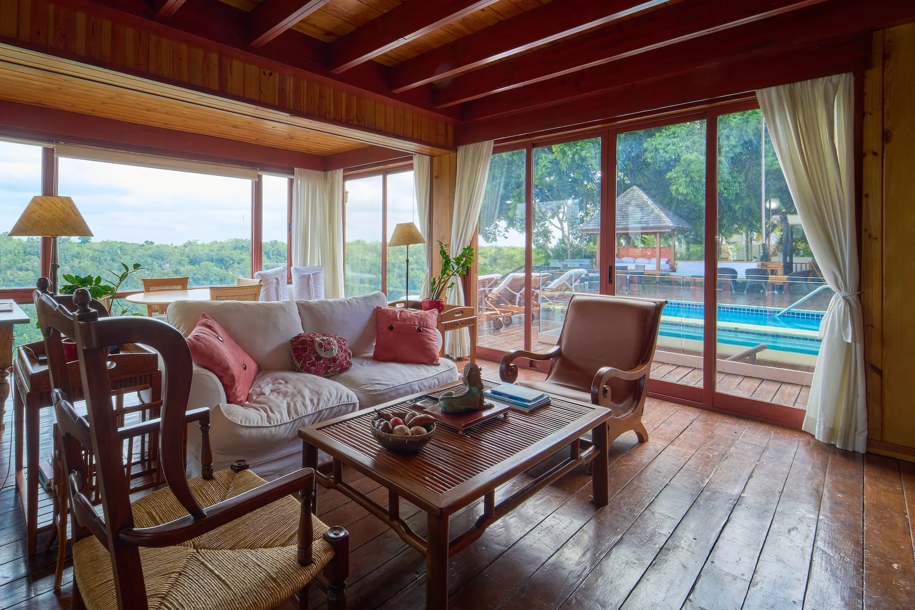 Una sala revestida de madera se abre a un patio junto a una piscina.
