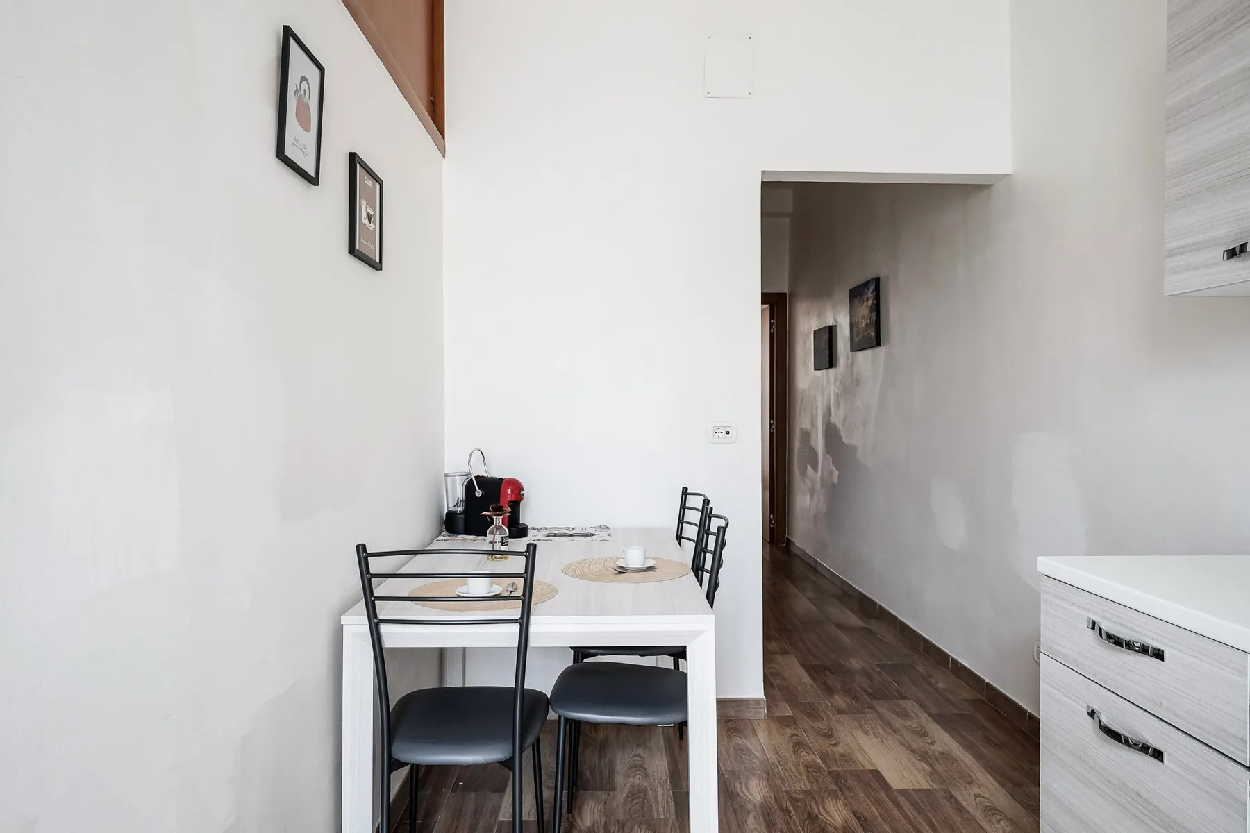 A small dining area with a table and chairs beside a hallway.