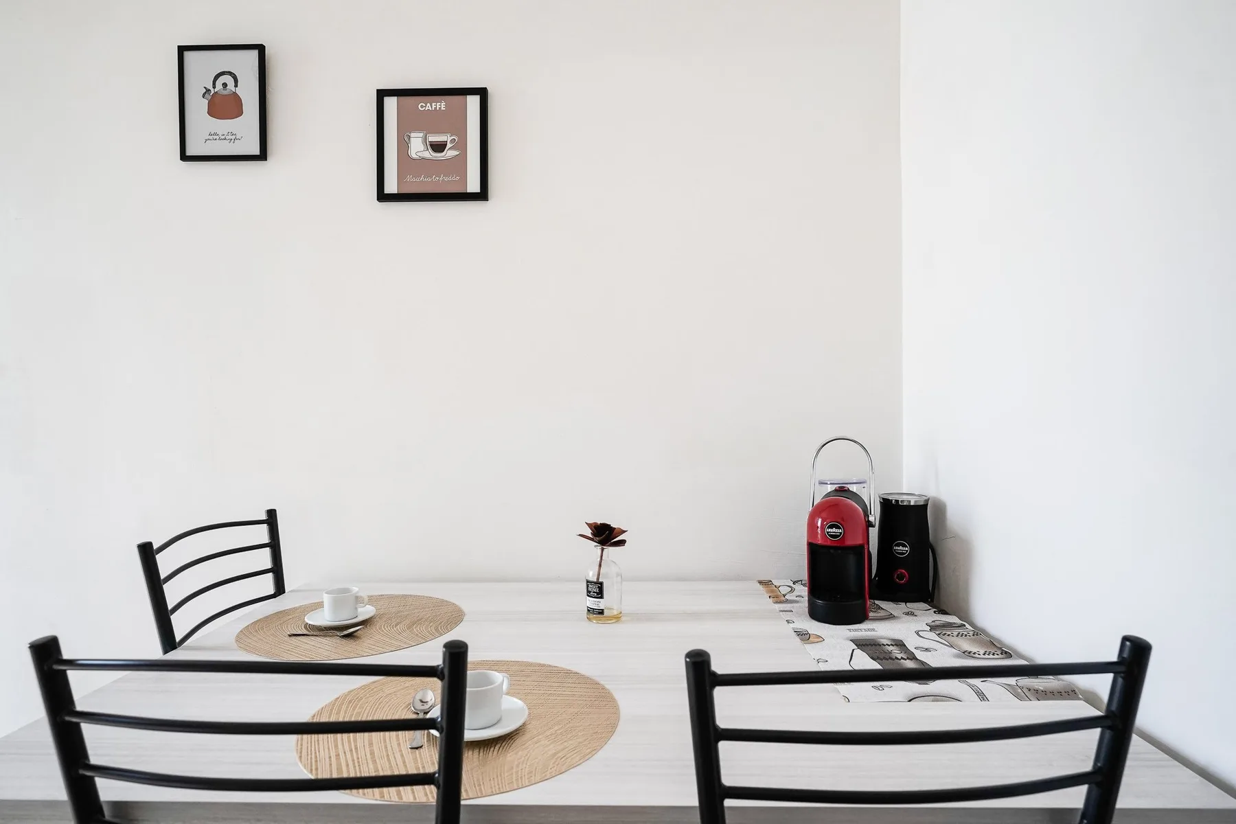 Un comedor con una mesa clara, asientos negros y cuadros en la pared.