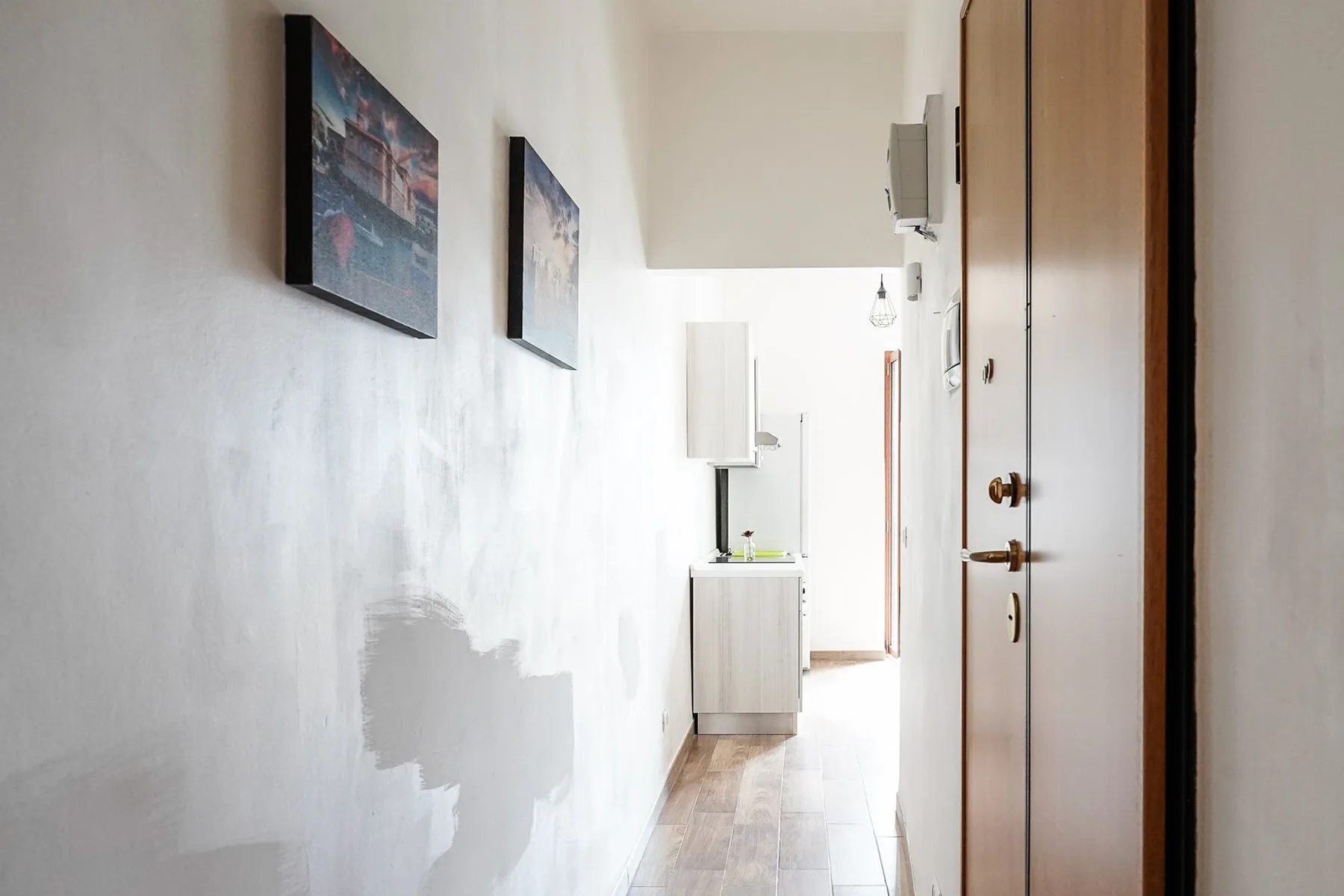 Un pasillo luminoso con cuadros en la pared y puertas a un lado.