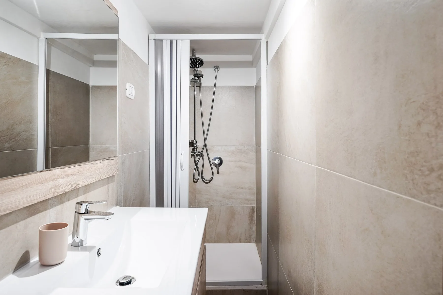 Un baño alicatado con un lavabo y una zona de ducha al fondo.
