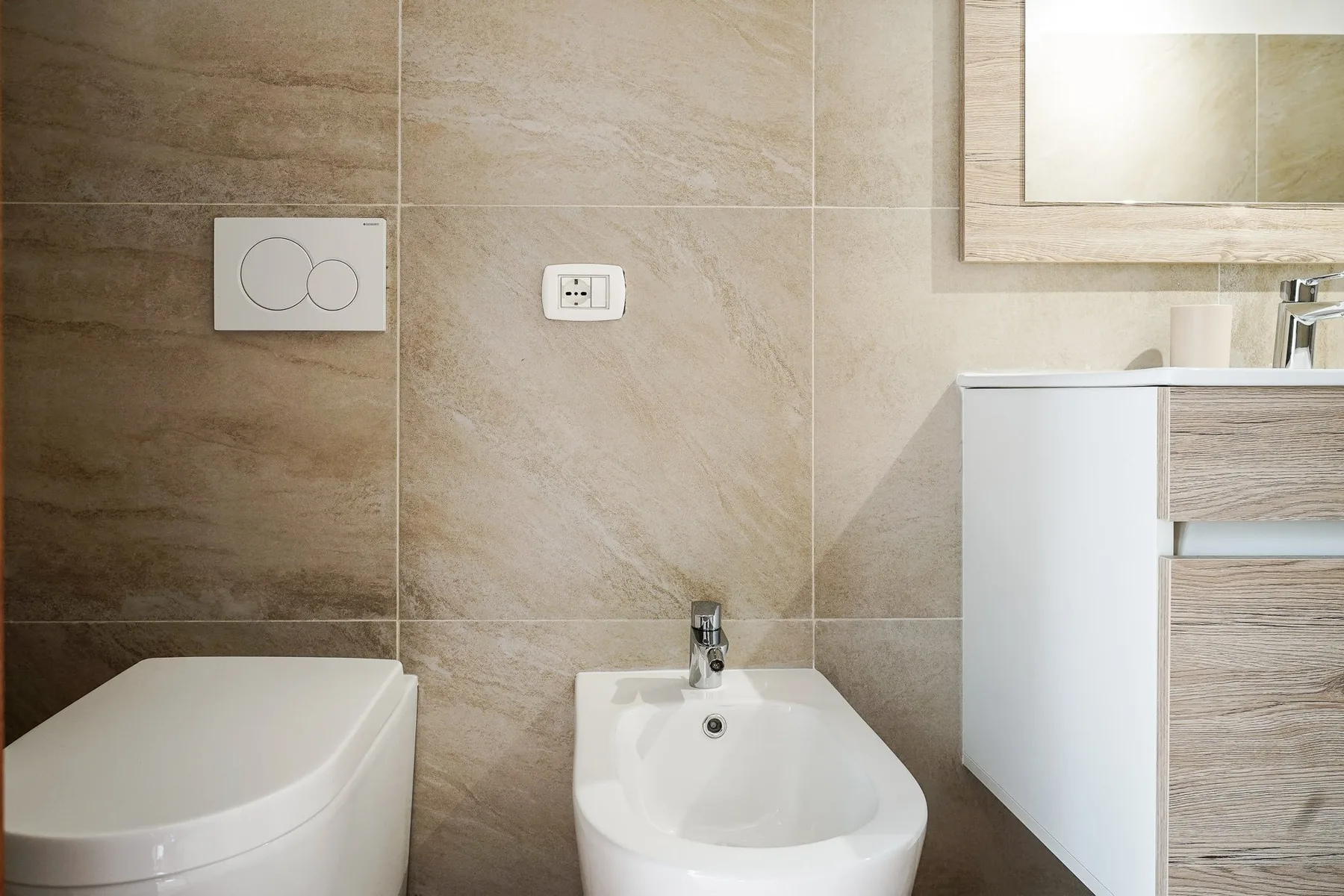 Un baño con azulejos, inodoro, bidé y lavabo.
