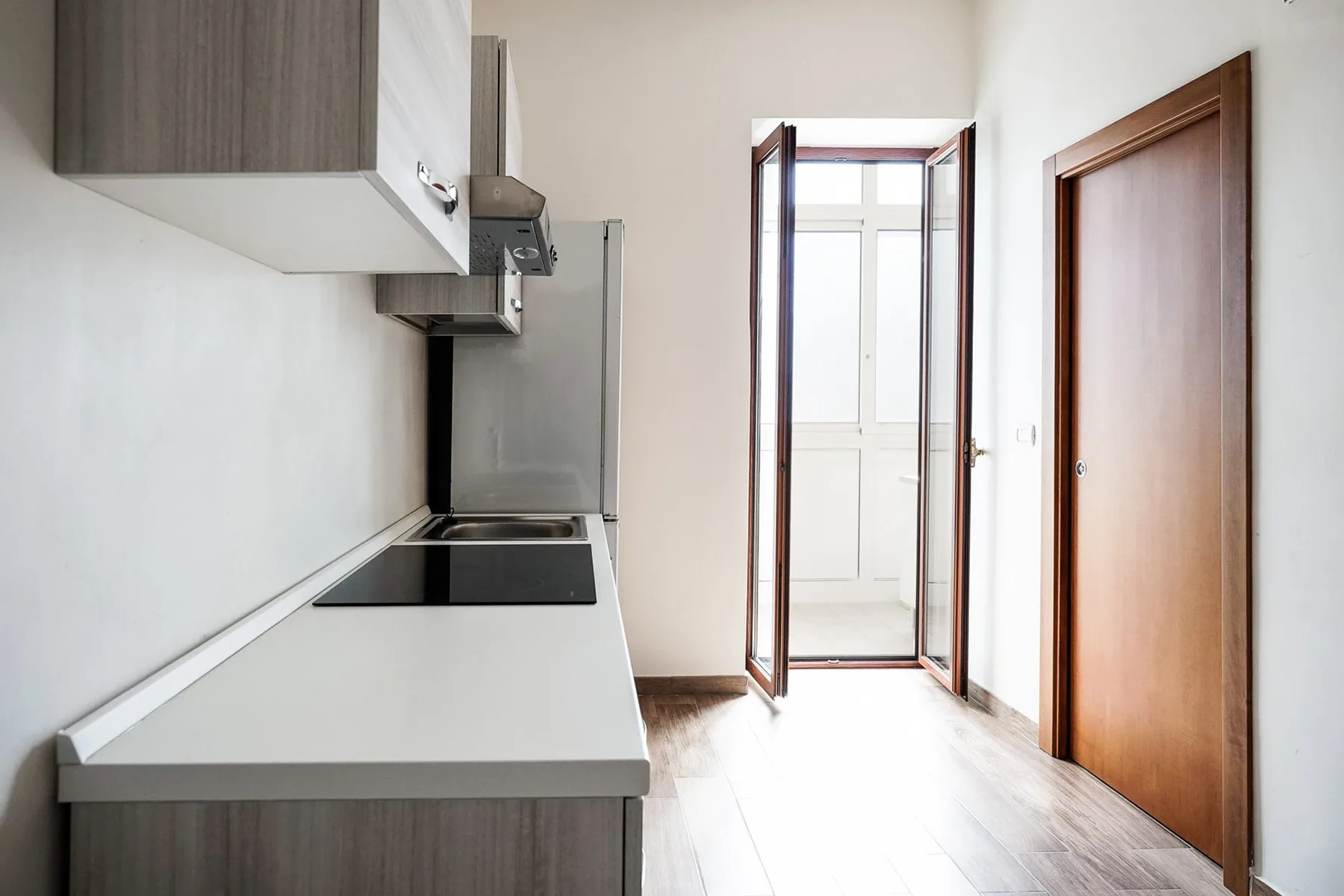 A narrow kitchen with a countertop and an open doorway at the far end.